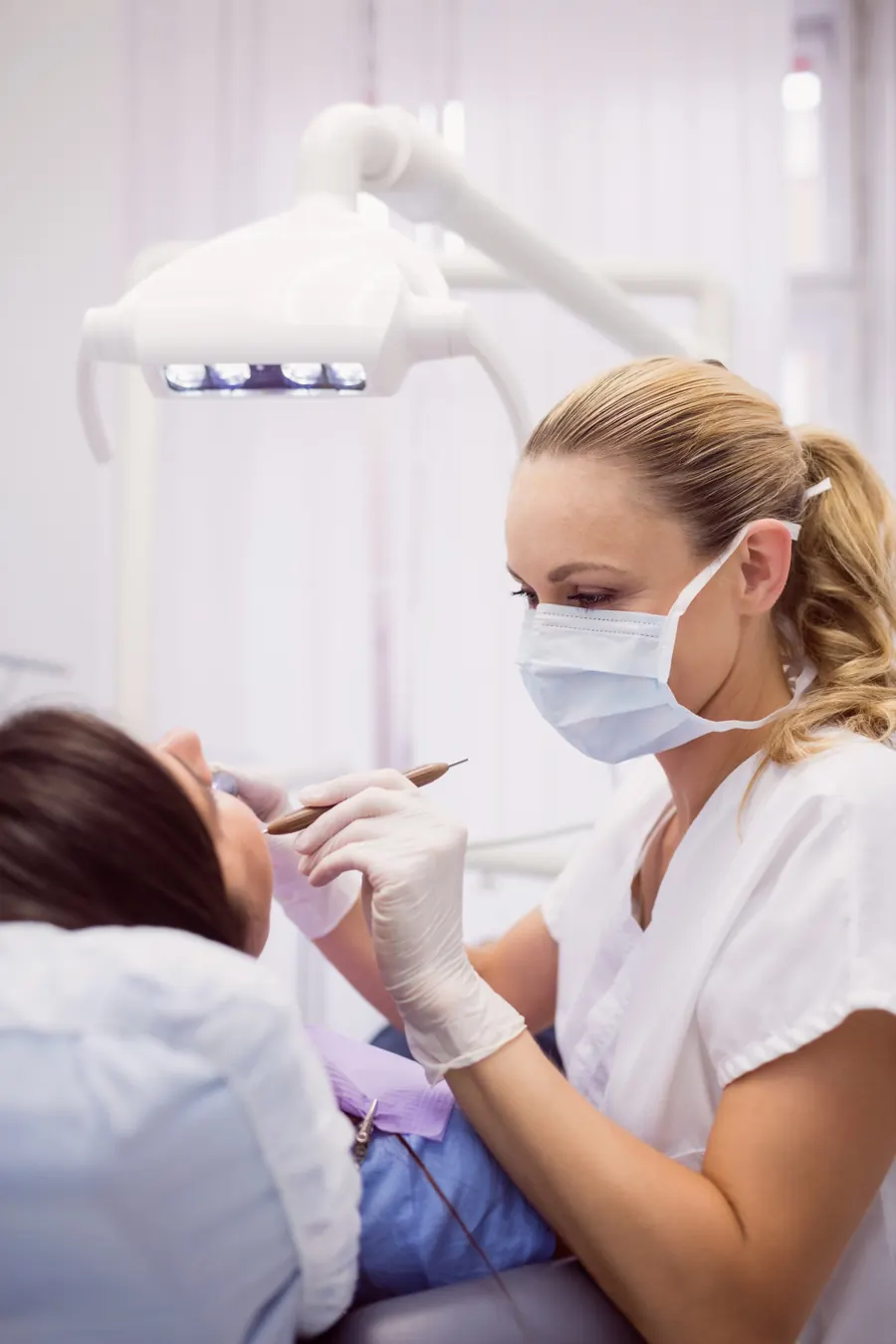 Odontóloga revisando a una paciente en el sillón dental