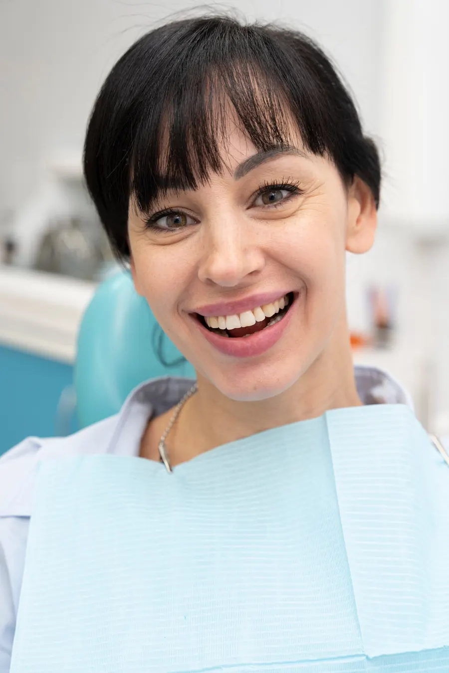 Paciente sonriendo en el sillón dental después de su tratamiento